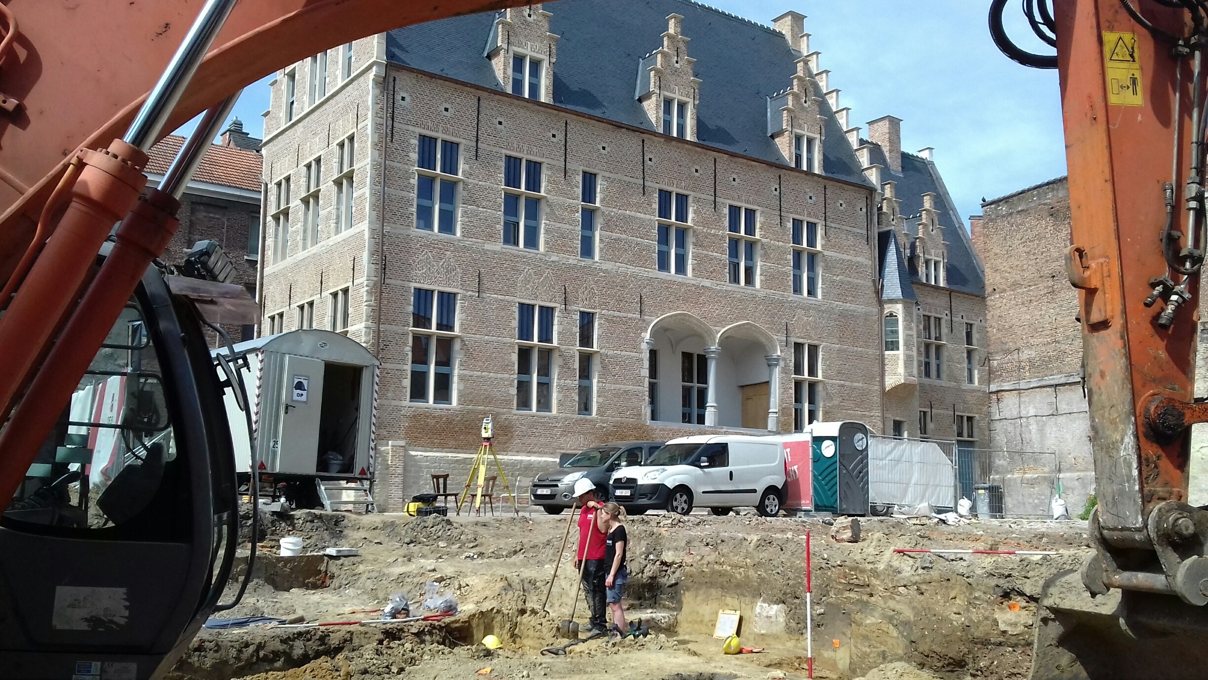 Archeologen van BAAC Vlaanderen aan het werk met op de achtergrond het gerestaureerde hof (© Stad Mechelen)