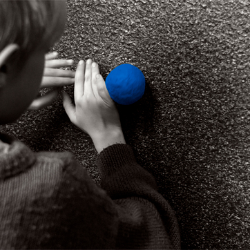 Jongen die met een blauwe bal op de muur mee zit te spelen
