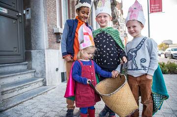 Drie kinderen met papieren mijter staan klaar om Sinte-Mette te zingen in de Mechelse straten.