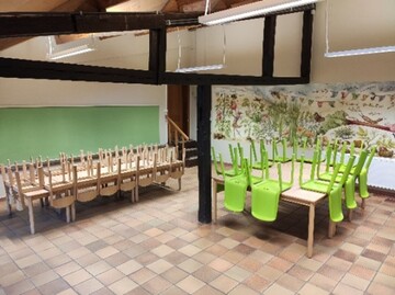 Overzicht van het zaaltje in de kinderboerderij: tafels en stoelen.