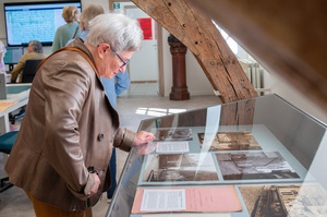 Een bezoeker bekijkt archiefstukken in een vitrine