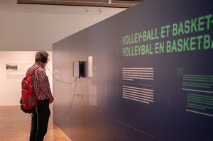 Een bezoeker kijkt met koptelefoon op het hoofd naar een video in de expo Sport en Sporters in KL Auschwitz in Kazerne Dossin
