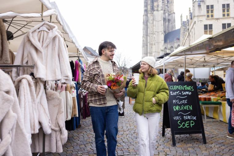 koppel man en vrouw loopt op de zaterdagmarkt met bloemen en koffie