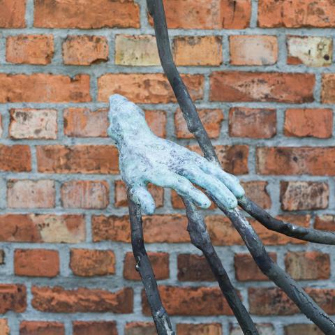 bronzen hand tegen bakstenen muur