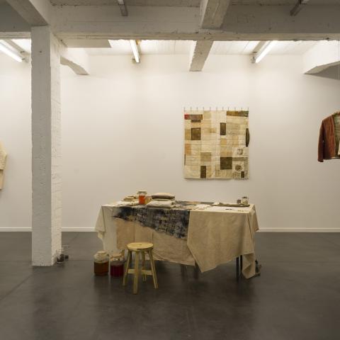 ruimte met in het midden een tafel, links en rechts hangen twee jassen 