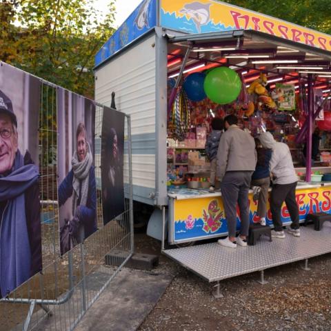 Twee portretten van wijkbewoners uit wijk Arsenaal die tentoongesteld staan naast een kraam op de wijkkermis