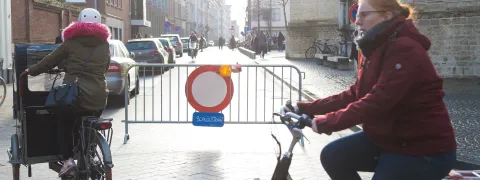 Fietsers fietsen voorbij de afsluiting van de schoolstraat.