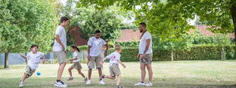 Kinderen spelen met de leiding op de jeugdbeweging.
