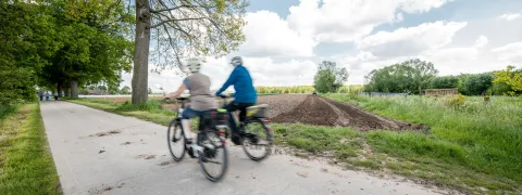 2 fietsers fietsen voorbij een veld op het Hombeeks plateau