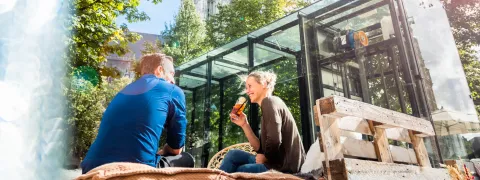 Een man een vrouw zitten gezellig iets te drinken op de Wollemarkt. Op de achtergrond zie je de Sint-Romboutstoren. 