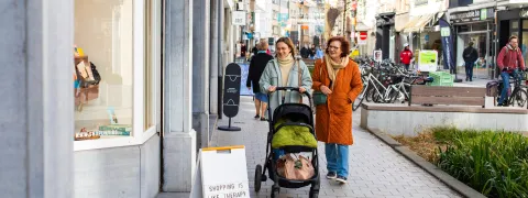 Shoppende dames met buggy aan etalage winkel